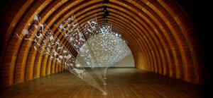Bild vergrößern: Total view of the installation by artist Zipora Rafaelov in the barrel vault of the Schafhof - European center for art of the district of Upper Bavaria. Delicate, fan-shaped installation made of 3D filament in wooden barrel vault. White motifs on seven panels stretched from the floor to the vault of the ceiling. Artist: Zipora Rafaelov; Photo: Klaus Lipa